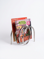 Human Error 001 Book Stand, a premium minimalist steel utility rest sitting on a modern studio workspace.